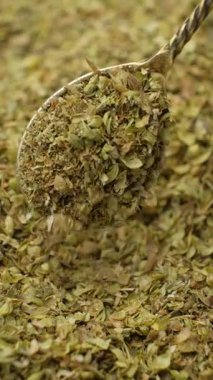 Kurumuş yeşil kekik kaşıktan dökülüyor, makro yavaş çekim dikey.