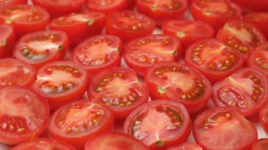 Taze kesilmiş küçük domateslerin yakın çekimi. Canlı Kırmızı Mutfak Döndürme.