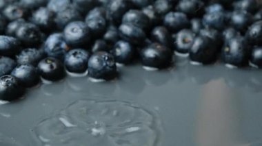 Taze yaban mersinleri suya dökülüyor. Su makro yavaş çekim sıçraması ile..