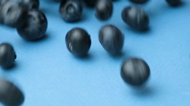 Taze olgun yaban mersinleri masada yuvarlanıyor, böğürtlen sıçraması, yavaş çekim makrosu