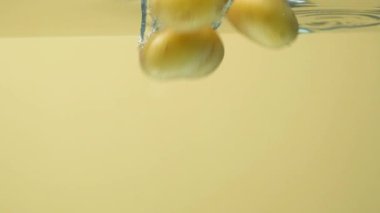 Taze organik soyulmamış patatesler suya düşer, su kabarcıkları, yavaş çekim.