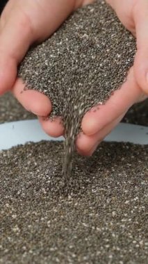 Chia tohumları dökülüyor. dikey ağır çekim. Organik süper gıda bileşeni