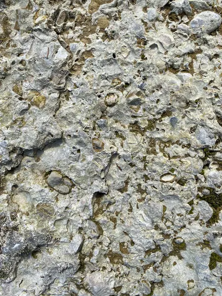 Weathered Stone Wall Texture Showing Cracks and Natural Vertical Patterns.
