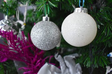 Noel ağacında asılı beyaz ve gümüş bir küre, tatil