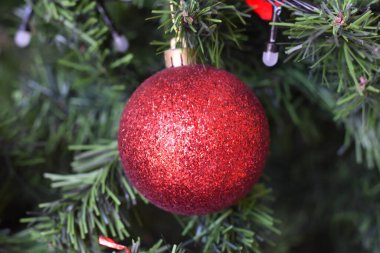 Ağaçta asılı kırmızı bir noel balosu resmi var, yeşil.