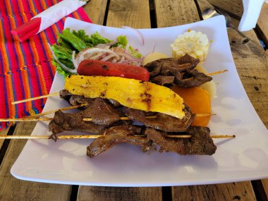 Tahta bir masa üzerinde salata ve mısırla birlikte Perulu antikalar ve yiyecek.