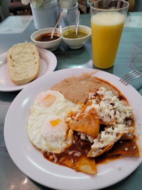 Kızarmış yumurta ve fasulyeyle birlikte kahve, ekmek ve yiyecek içeren biberlerin dikey görüntüsü.