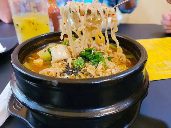 Culinary Delight: Savoring Korean Ramen with Chopsticks on a Black Plate, Restaurant