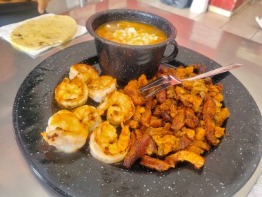 Salamura edilmiş karides ve domuz eti, yanında tortilla ve fasulye çorbası, restoran.