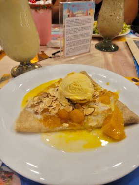 Üzerine tatlı mango, kızarmış badem ve bir kepçe vanilyalı dondurma serpiştirilmiş, mango soslu, dikey