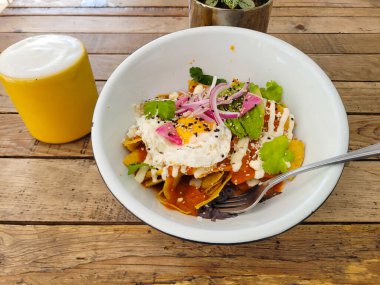 Baharatlı chilaquiles 'ın üzerine mükemmel pişirilmiş, krema serpiştirilmiş ve susam tohumları serpiştirilmiş,