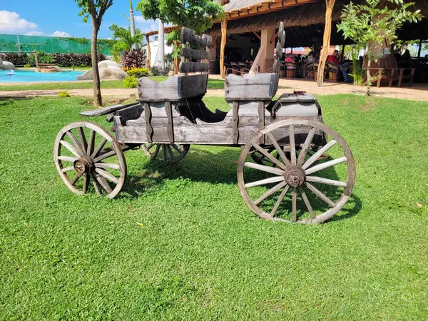 stock image Rustic old wooden cart displayed outdoors on vibrant green grass under a sunny sky, Mexico