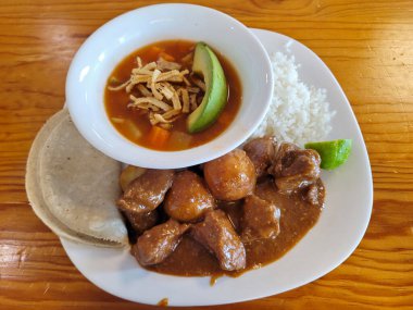 Lezzetli soslu, lezzetli bir biftek güveci, yumuşak beyaz pirinç ve klasik tortilla çorbası ile servis edilir.