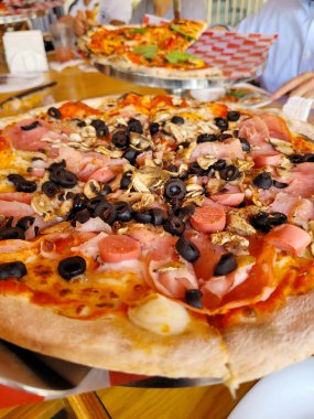 Çeşitli malzemeler ve erimiş peynirle süslenmiş lezzetli bir pizzanın dikey görüntüsü