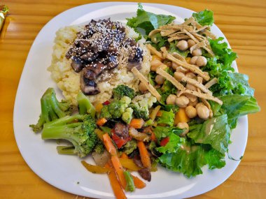 Buharda pişmiş sebzeli besleyici vejetaryen yemeği, pirinçli lezzetli mantarlar ve nohutlu taze yeşil salata.