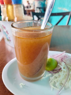 Bir bardak Caldo Michi, klasik Meksika balık çorbası, limon ve soğanla servis edilir.