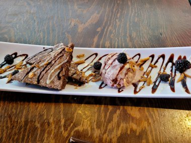 Çilekli dondurmayla servis edilen şerbetli çikolatalı brownie dilimleri, tatlı.