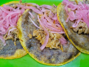 Lezzetli Panuchos 'un yakın çekimi, Yucatecan spesiyalitesi, canlı soğanlarla süslenmiş.