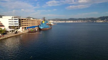 Okyanus üzerinden Acapulco 'nun hareketli denizcilik terminaline yaklaşan bir drone videosu şehir ve deniz manzarasını gözler önüne seriyor.