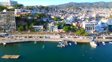 Güzel kıyı şeridi boyunca uçan bir İHA 'nın yan panoramik görüntüsü Acapulcos manzaralı plajları ve şehir zeminini vurguluyor.