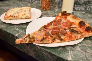Biberli ve soğanlı bir dilim pizza New York 'ta mermer tezgahta duruyor.