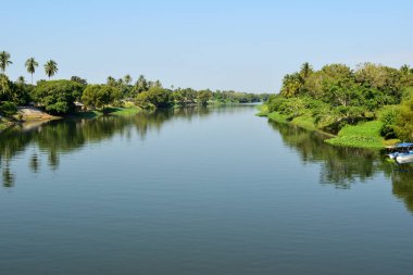 La Antigua nehri, ağaçların ve evlerin yeşil yansımasıyla. Su sakin ve huzurlu.