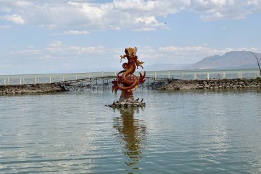 Jocotepec, Mexico - March 18 2023: A Quetzalcoatl statue is floating in pier in Chapala lake. The water is calm and the sky is clear clipart