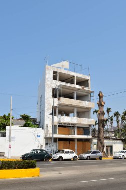 Acapulco, Meksika - 27 Nisan 2024: Önünde bir sürü penceresi ve otoparkı olan yüksek bir bina. Bina boş ve bir sürü yeri var.