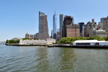 Ortasında büyük bir bina olan New York silueti. Su sakin ve gökyüzü berrak.