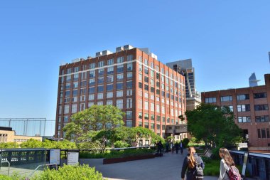 New York, ABD - 17 Mayıs 2023: Bir grup insan Hudson Lisesi 'nde büyük bir tuğla binanın önünde yürüyor. Gökyüzü açık ve güneş parlıyor.