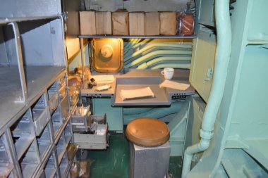 New York, ABD - 17 Mayıs 2023: Masası ve sandalyeli uçak gemisi korkusuz küçük bir oda. Masada bir fincan ve birkaç kağıt var. Oda loş ve loş.