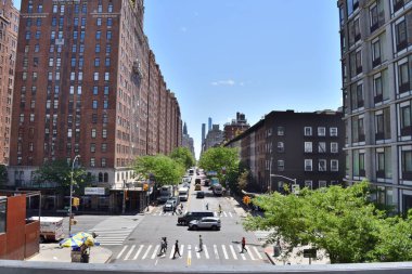 New York, ABD - 17 Mayıs 2023: Yaya geçidi ve birkaç yayası olan işlek bir şehir caddesi. Sokak yüksek binalarla dolu ve birkaç araba caddede ilerliyor.