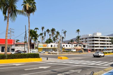 Acapulco, Meksika - 27 Nisan 2024: Arkasında sarı bir bina olan Coastal Avenue. Caddede bir araba sürüyor..