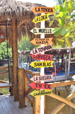 San Blas, Meksika - 25 Mayıs 2024: Farklı yönleri gösteren birçok farklı renkli okları olan bir işaret. Tabela İspanyolca. İsimleri falan yazıyor.