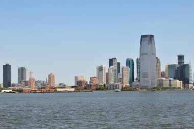 Ortasında büyük bir bina olan New York silueti. Su sakin ve gökyüzü berrak.