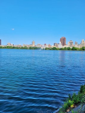 Central Park Gölü manzaralı. Manhattan gökdelenli. New York 'ta aydınlık bir yaz gününde.