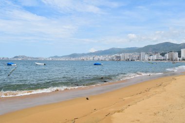 Acapulco 'daki Icacos plajı, üzerinde açık mavi bir gökyüzü ve hafif bir meltem esintisiyle güzel ve sakin bir yerdir. Su sakin ve durgun. Yüzeyinde yüzen birkaç tekne var..