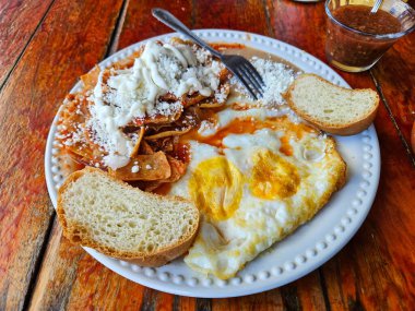 Kırmızı soslu Chilaquiles yanında fasulye, sahanda yumurta ve ekmek, Meksika