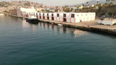 İnsansız hava aracı okyanusun üzerinde çaprazlama uçuyor, Acapulco 'nun deniz terminalini ve engin denizi görüyor.