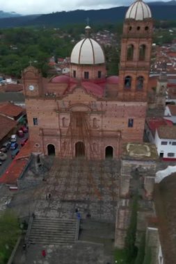 Tapalpa 'da kilisenin etrafında daireler çizerek merkezi meydanı ve kasabayı çevreleyen dikey drone atışları.