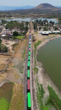 Trenin Jalisco, Meksika 'daki Valencia Barajı' nı çevreleyen arazide ilerlediğini gösteren dikey bir drone görüntüsü var.