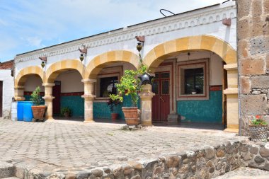 Meksika, Jalisco 'daki San Lucas Evangelista kilisesinin yanındaki avluda taş kemerler ve renkli fayanslar var.