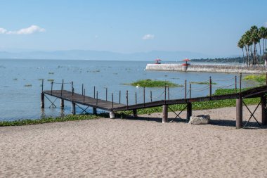 Jalisco, Meksika 'daki Kumlu sahil ve sakin Chapala Gölü üzerindeki manzara ahşap rıhtım.