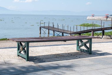 Chapala Gölü boyunca Jalisco, Meksika 'da rıhtımı ve dağları olan huzurlu ahşap bir bank.
