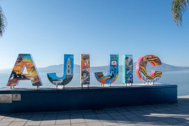 Ajijiç, Meksika - 26 Ocak 2025: Kültürel sanat eserleriyle süslenmiş turist işareti, Ajijiç, Jalisco 'da dağlarla çevrili gölde duruyor