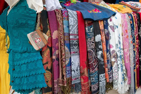 Guadalajara, Meksika - 2 Şubat 2025: El yapımı işlemeli elbiseler, şallar ve tekstil ürünleri Guadalajara, Jalisco şehir merkezindeki bir sokak tezgahında sergilenmektedir.