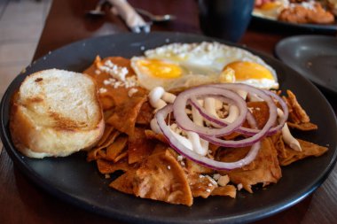 Geleneksel Meksika kahvaltısı chilaquiles rojos ve sahanda yumurta ve tost, sıradan bir yemek düzeninde servis edilir.