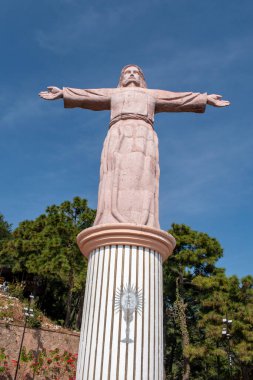 Taxco, Meksika - 21 Aralık 2024: Taxco, Guerrero, Meksika 'daki İsa Anıtı, açık mavi gökyüzünün altında kolları açık duruyor.