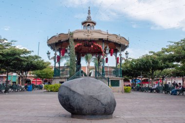 Jocotepec, Meksika - 22 Şubat 2025: Jocotepec şehir meydanındaki tarihi büfe ve büyük taşlar ağaçlar ve banklarla çevrili