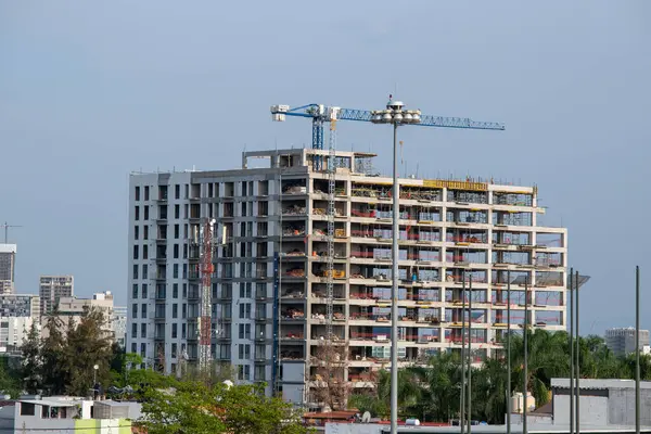 Zapopan, Meksika - 5 Haziran 2025: Şehir yapıları tarafından çevrelenmiş, inşaat halindeki yüksek katlı beton bina ve kentsel alandaki kule vinci